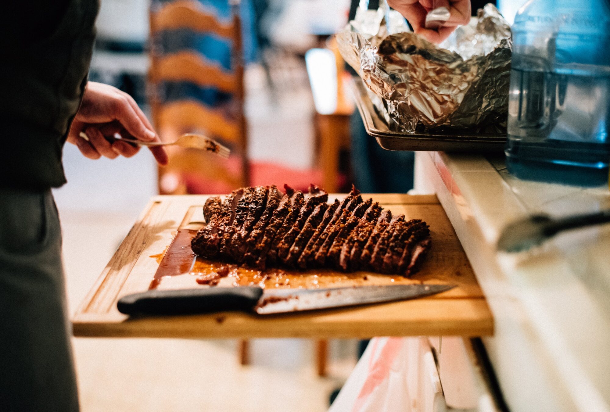 A person cutting up meat on top of a wooden board.
